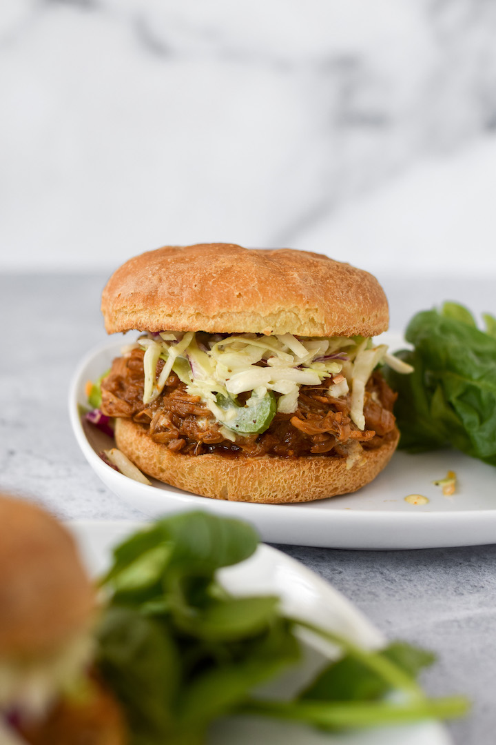 These vegan "pulled pork" inspired sandwiches feature sweet & smoky BBQ spiced jackfruit topped with a creamy coleslaw on a fluffy gluten-free bun. This gluten-free, dairy-free, and vegan recipe is sure to be a hit at your next summer BBQ!