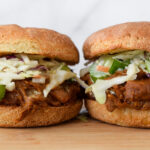 These vegan "pulled pork" inspired sandwiches feature sweet & smoky BBQ spiced jackfruit topped with a creamy coleslaw on a fluffy gluten-free bun. This gluten-free, dairy-free, and vegan recipe is sure to be a hit at your next summer BBQ!