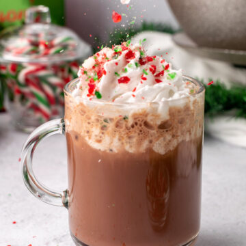 candy cane pieces falling on a peppermint mocha