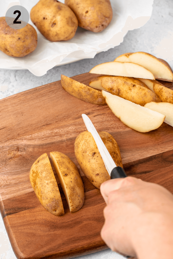 a knife slicing half a russet potato into quarters