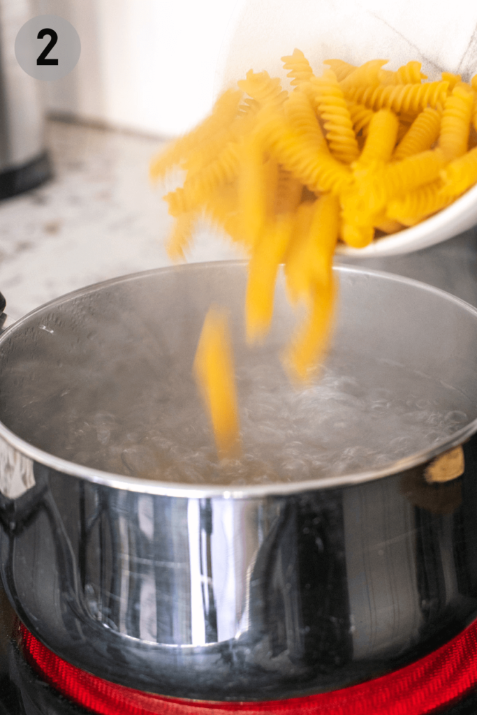 rotini pasta being poured into boiling water