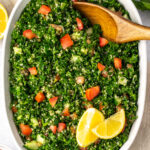 quinoa tabbouleh in a white dish with a wood spoon