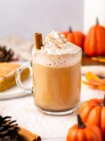 vegan pumpkin spice latte with a cinnamon stick and pumpkins around