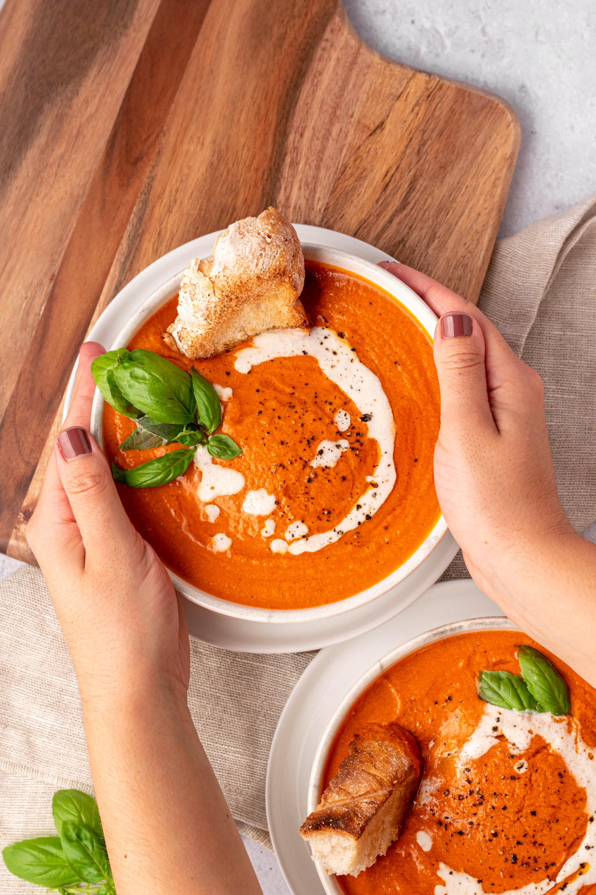 hands grabbing a bowl of gluten free tomato soup
