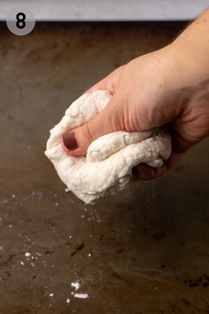 hand squishing bagel dough