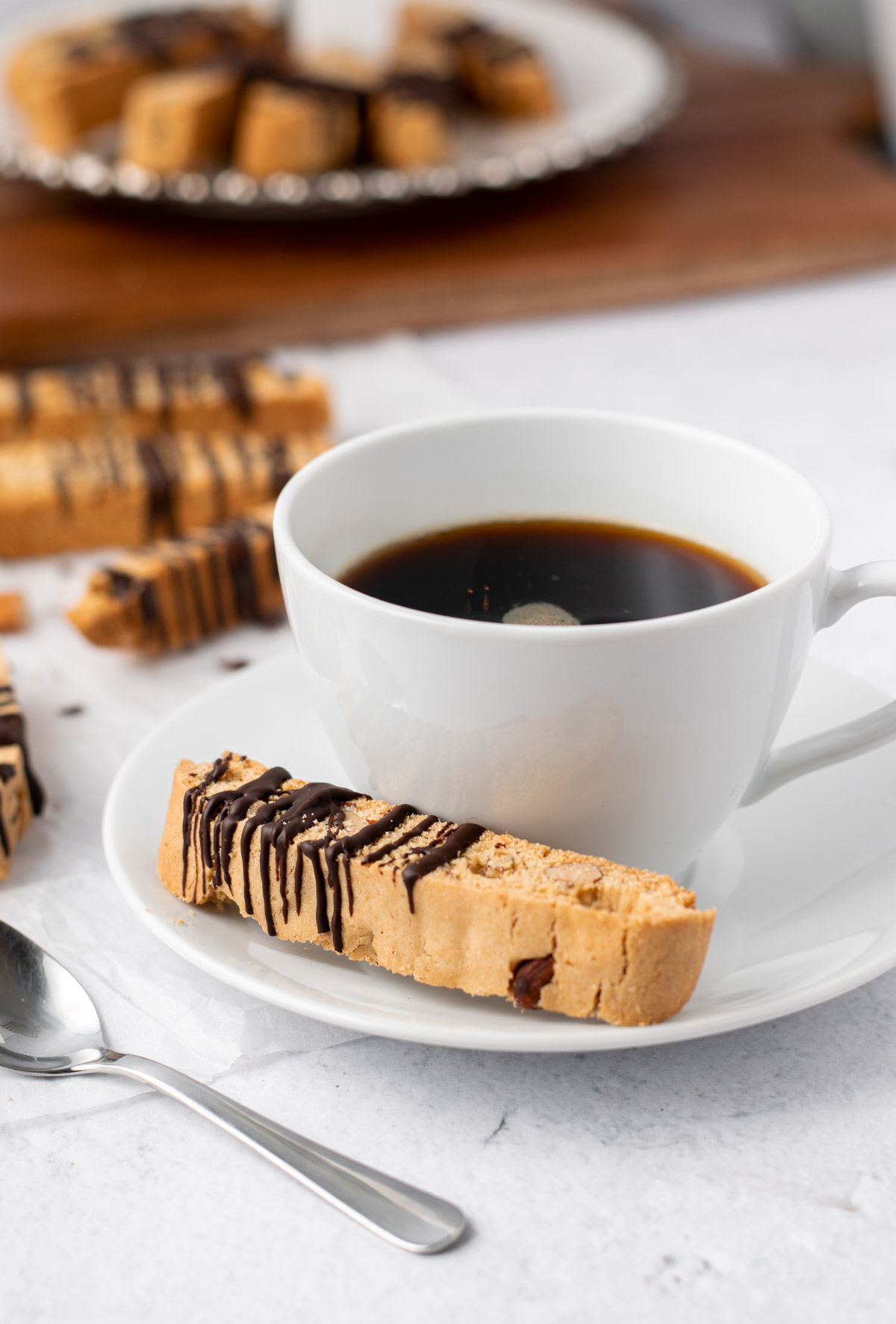 gluten free almond biscotti on a saucer with a cup of coffee