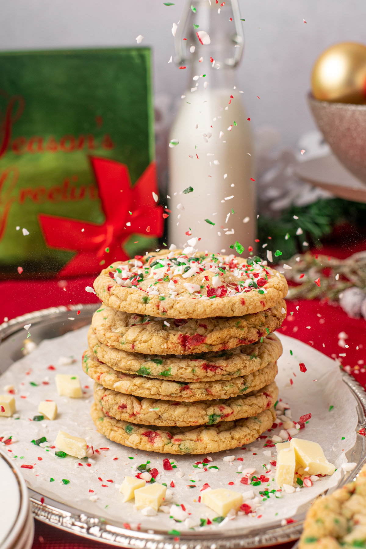 candy cane pieces falling on a stack of candy cane white chocolate cookies