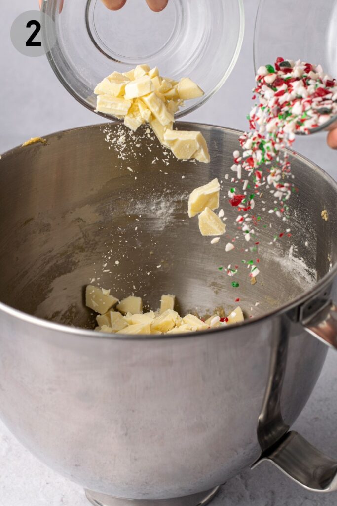 pouring white chocolate and candy cane chunks into cookie dough