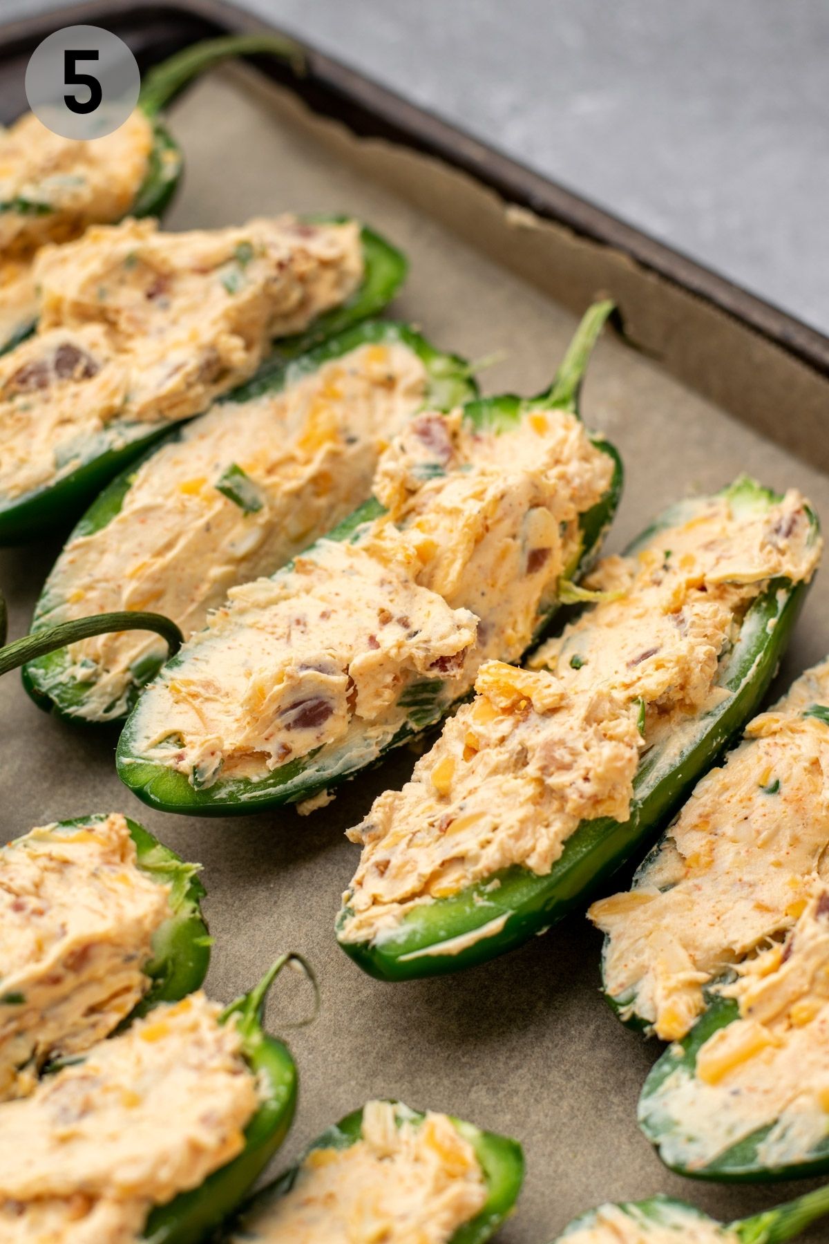 jalapeño halves filled with cream cheese mixture on a baking sheet