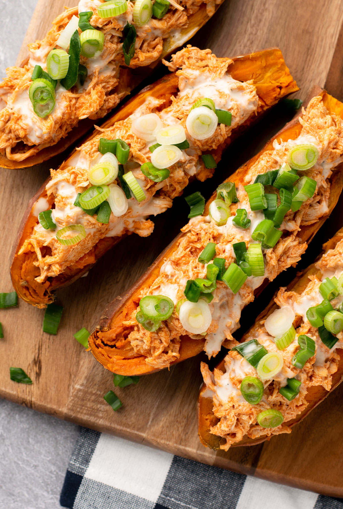 top view of sweet potatoes topped with buffalo chicken and green onions