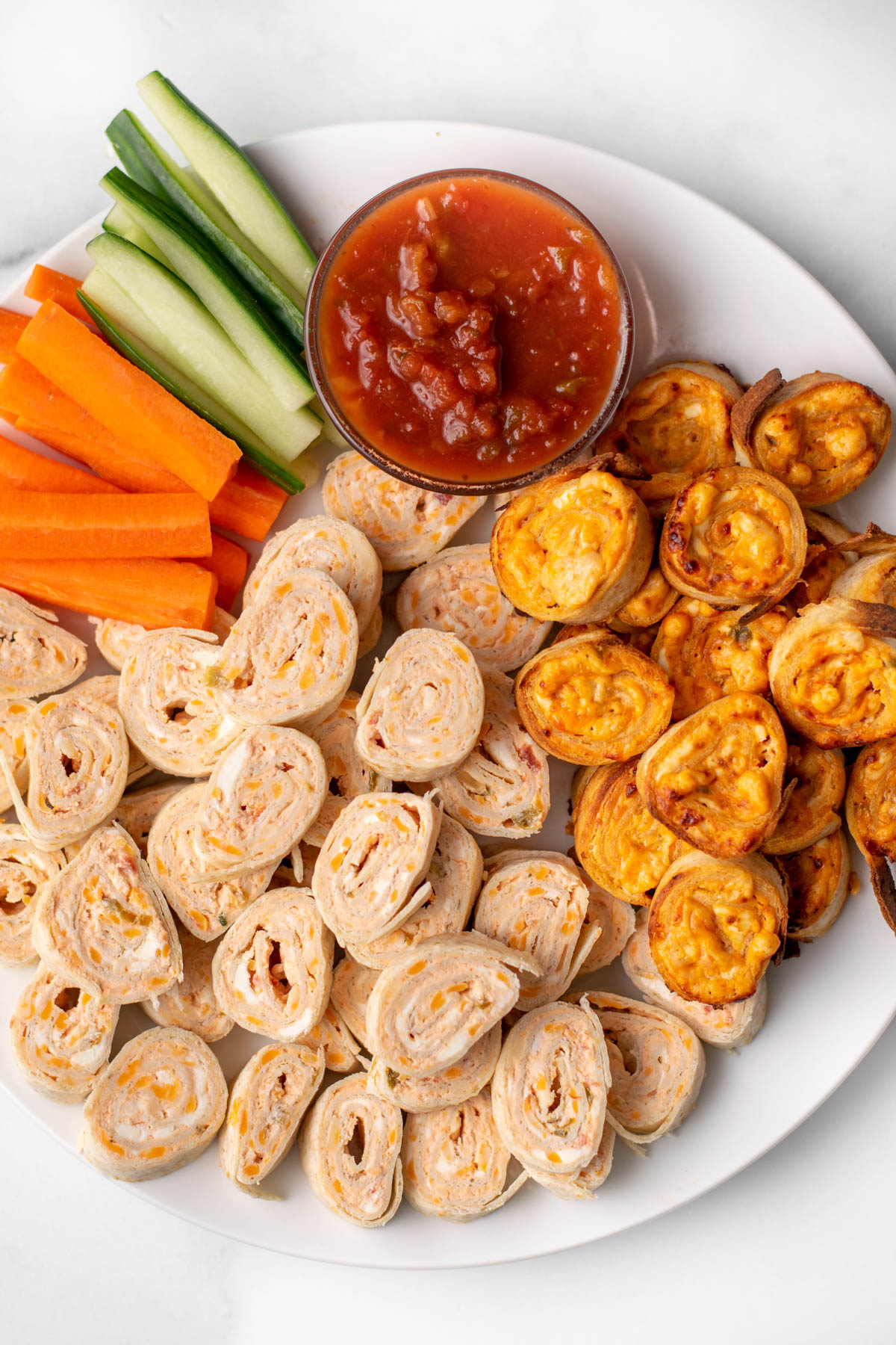 top view of baked and unbaked salsa pinwheels on a plate