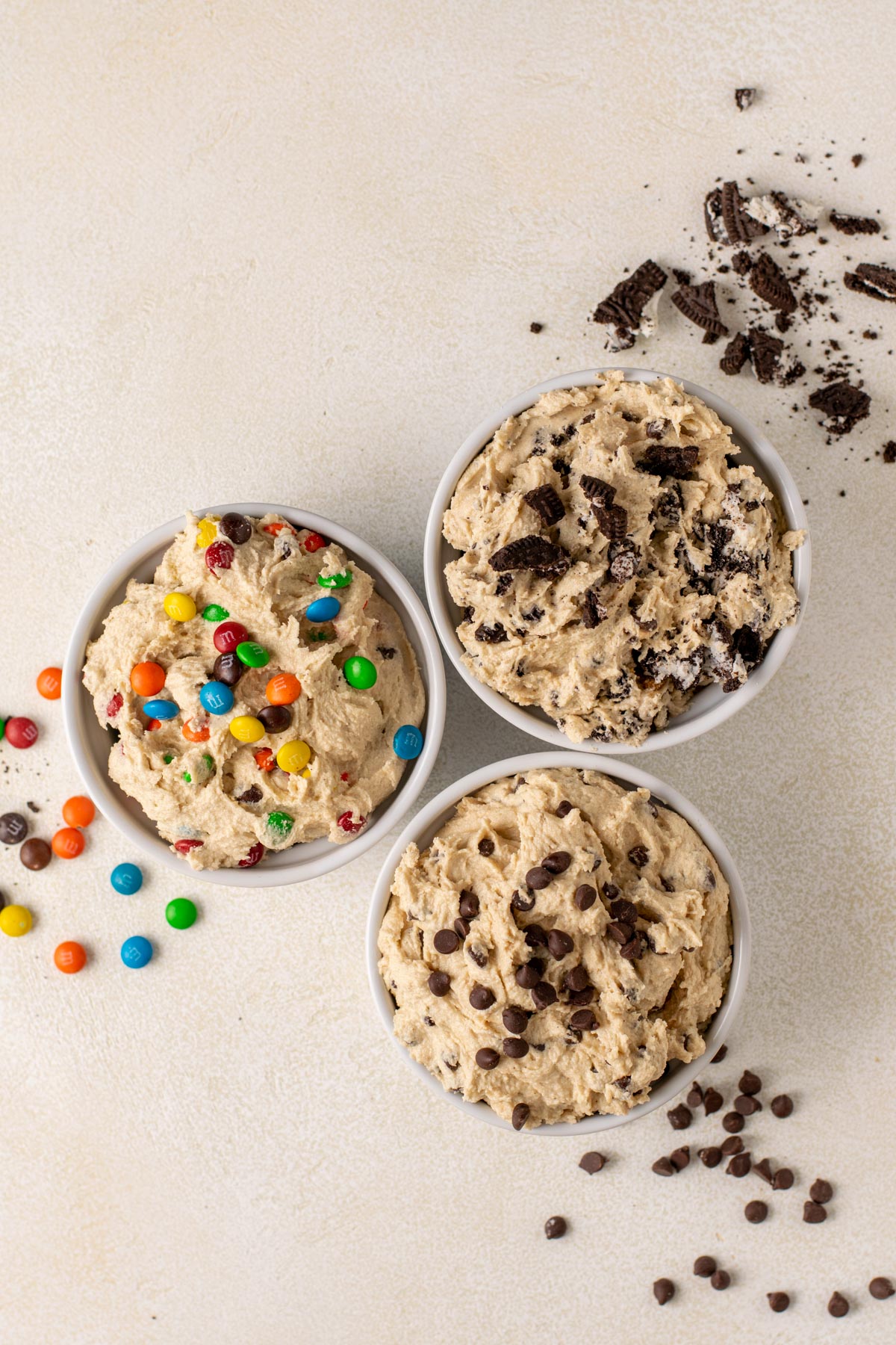 3 flavours of gluten free cookie dough in white ramekins: m&m, oreo, and chocolate chip.
