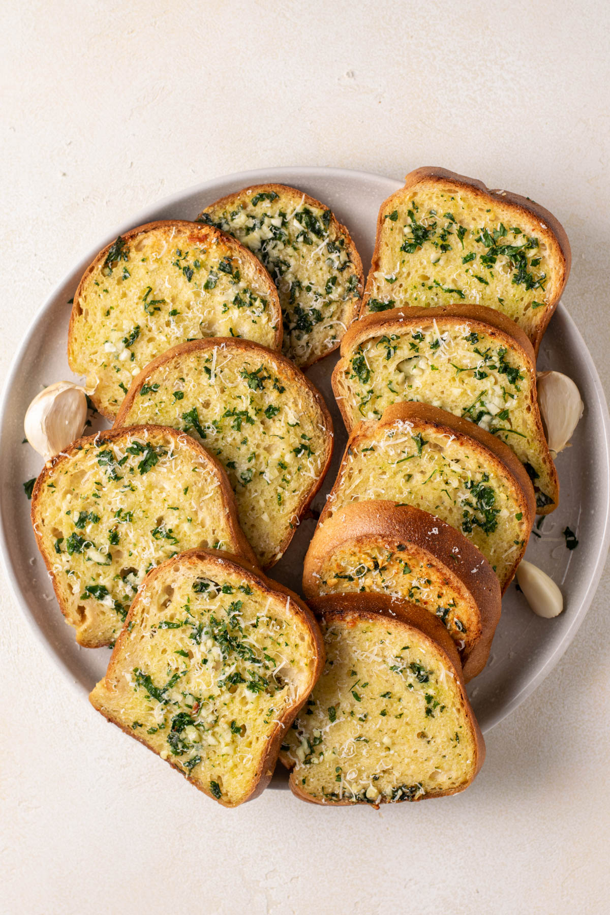 gluten free garlic bread on a plate with some garlic cloves.