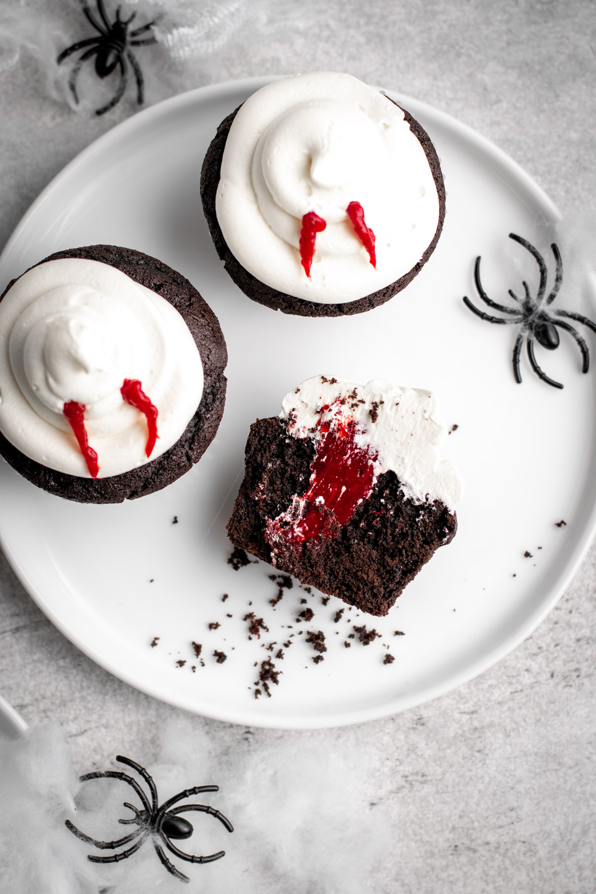 vampire bite cupcakes on a white plate with one sliced in half.