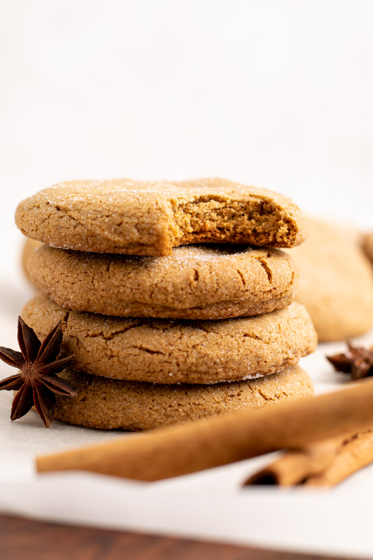 stack of gluten free ginger molasses cookies, the top one with a bite missing.