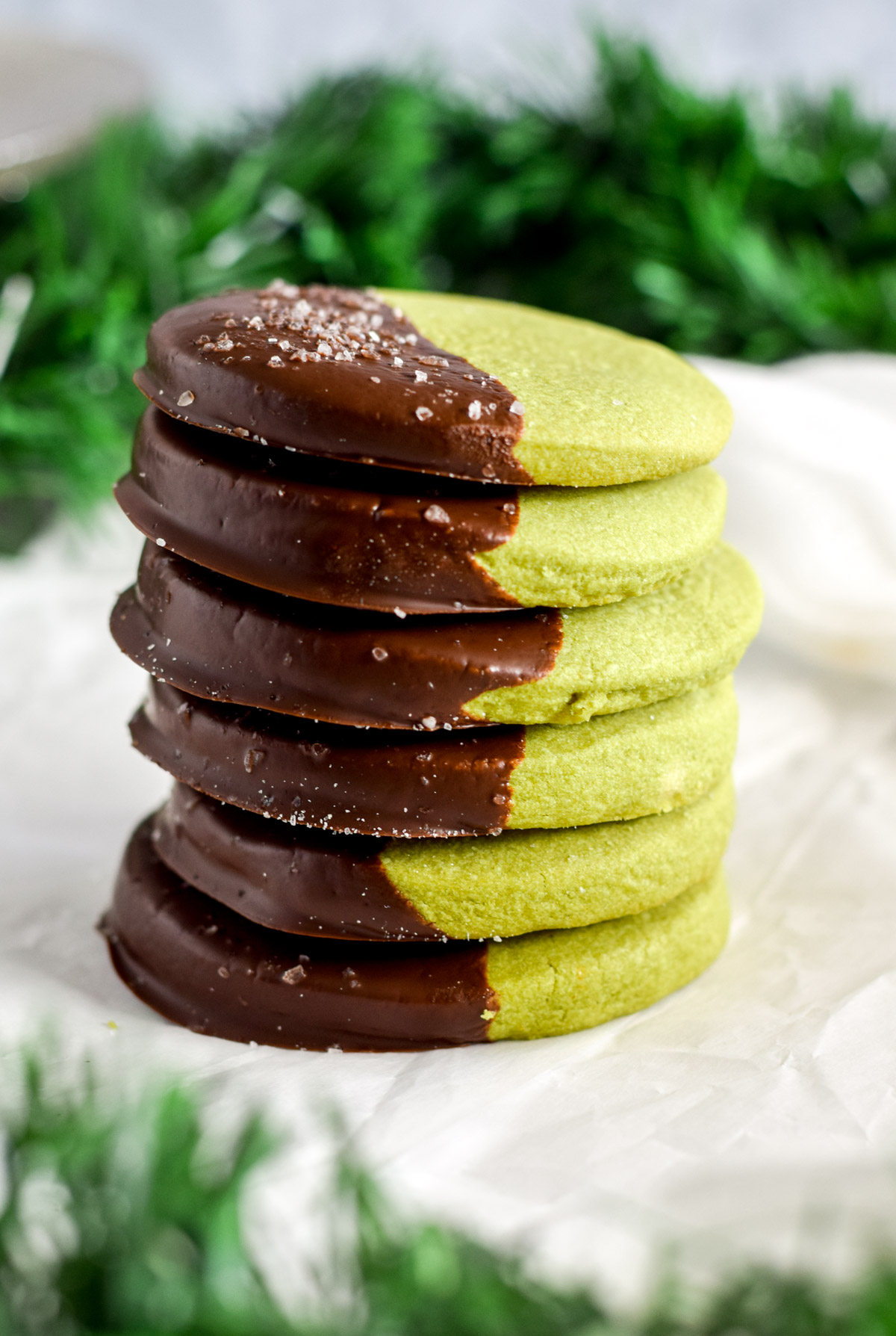 a stack of round chocolate dipped matcha shortbread cookies.