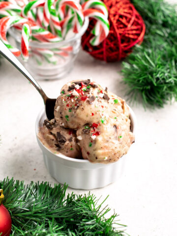 scoops of candy cane nice cream in a ramekin with a spoon.