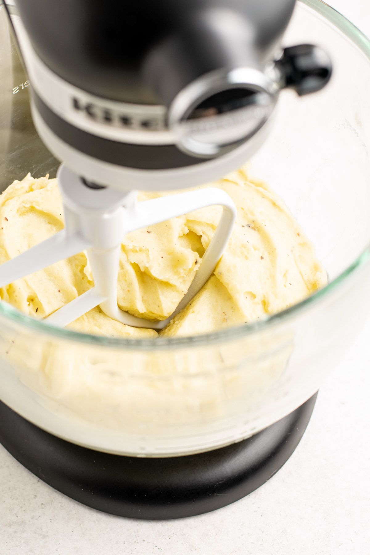 mashed potatoes being mashed in a kitchenaid stand mixer.