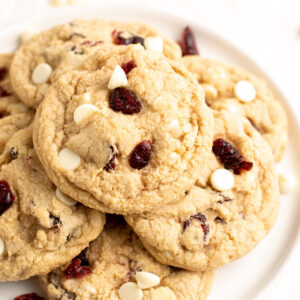 stack of gluten free white chocolate cranberry cookies on a white plate.