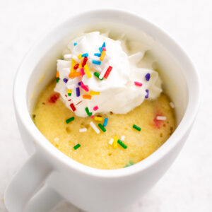 gluten-free vanilla funfetti mug cake with whipped cream and sprinkles on top.