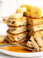 close up cross section of a stack of 4 vegan pancakes with banana slices on top.
