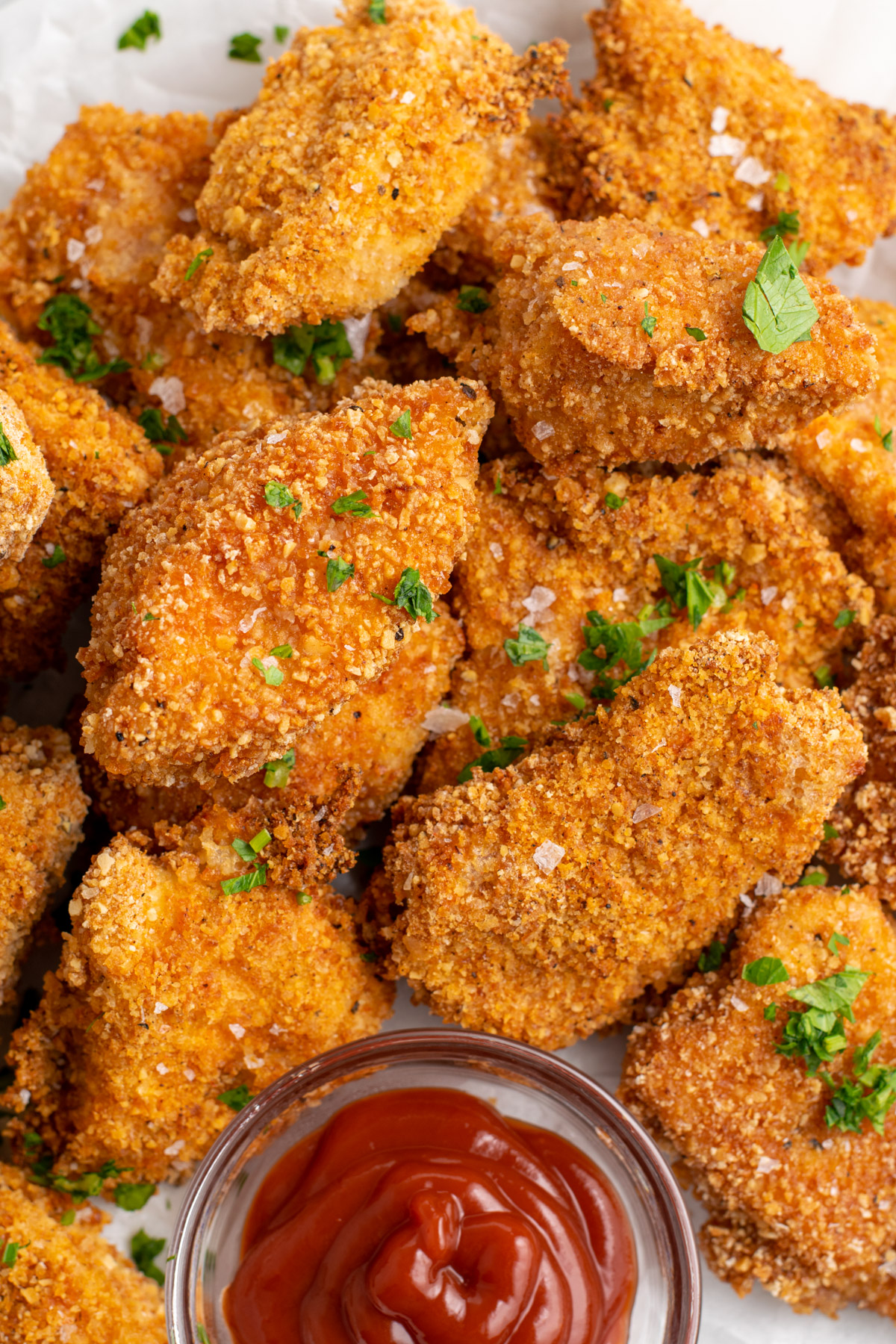 close up of gluten free chicken nuggets with a small bowl of ketchup.