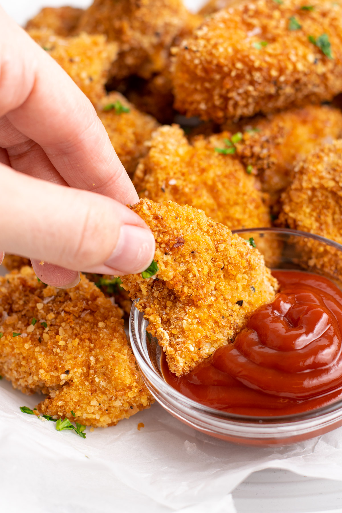 hand dipping a chicken nugget into ketchup.